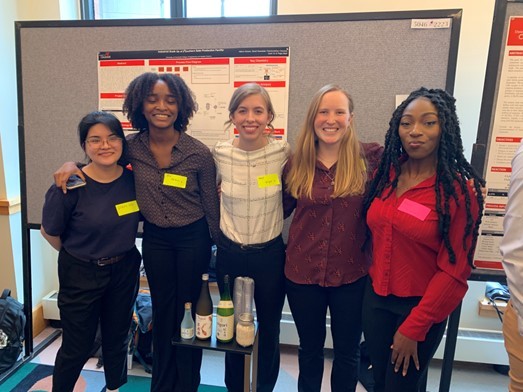 college students pose in front of poster